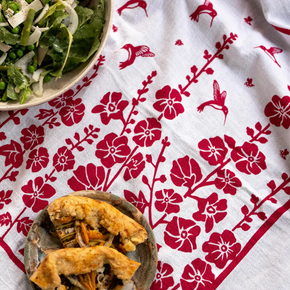 Two bowls of food on a white dish towel with red floral patterns