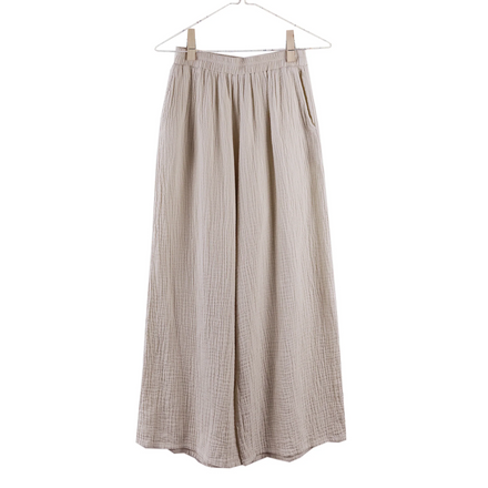 Beige gauze pants on a hanger against a white background