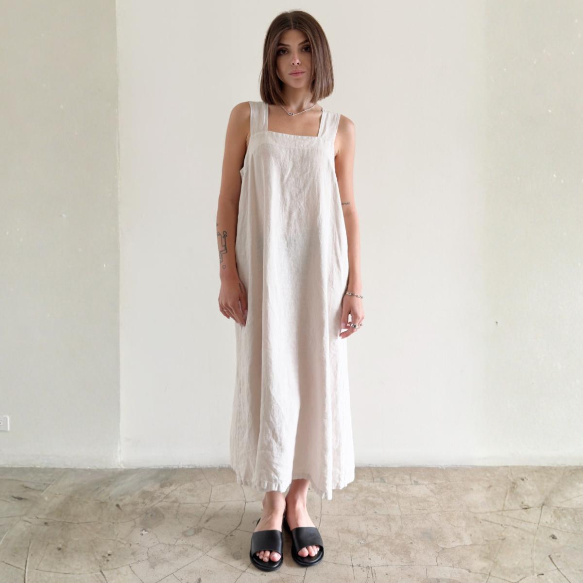 Woman wearing a white sleeveless dress against a plain background