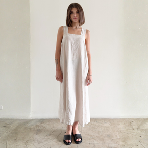 Woman wearing a white sleeveless dress against a plain background