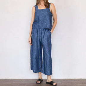 Woman wearing a blue denim jumpsuit against a white background