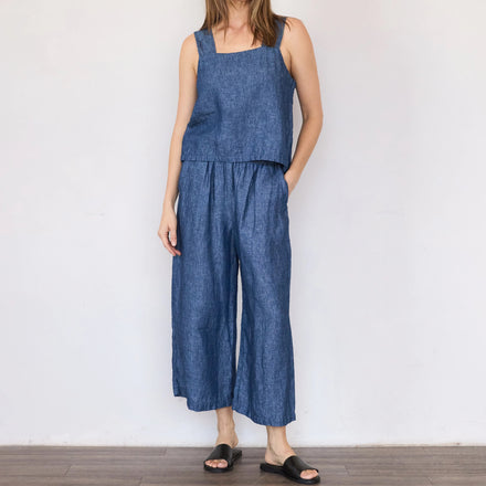Woman wearing a blue denim jumpsuit against a white background