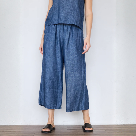 Person wearing a blue denim outfit with wide-leg pants against a white background