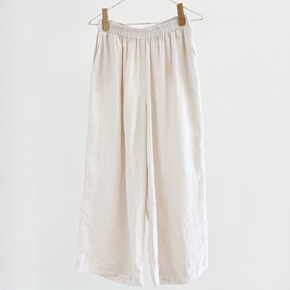 Beige pants hanging on a wooden hanger against a white background