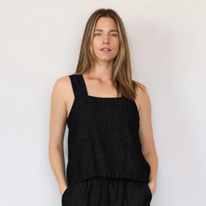 Woman wearing a black sleeveless top and black pants against a plain background