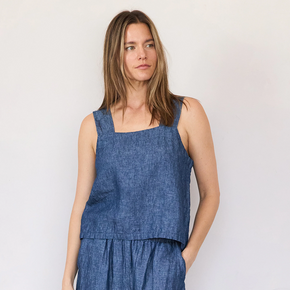 Woman wearing a blue denim tank against a plain background