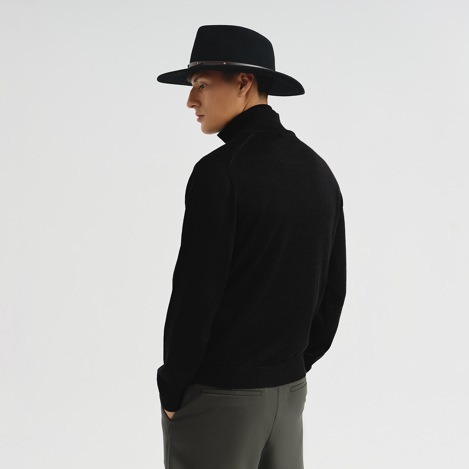 Person wearing a black hat and black sweater on a white background