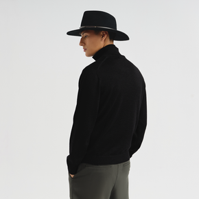 Person wearing a black hat and black sweater on a white background