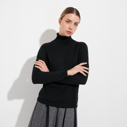 Woman wearing a black turtleneck sweater against a white background