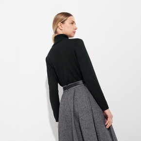 Woman wearing a black turtleneck and gray skirt on a white background
