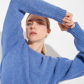 Woman wearing a blue sweater against a white background