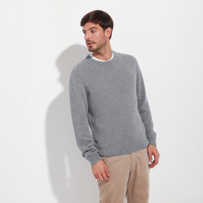 Man wearing a gray sweater and beige pants on a white background