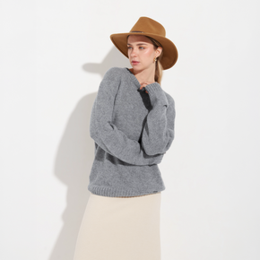 Woman wearing a gray sweater and brown hat against a white background