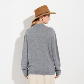 Person wearing a gray sweater and beige hat on a white background