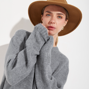 Woman wearing a gray sweater and brown hat on a white background