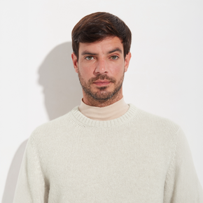 Man wearing a cream sweater against a plain background