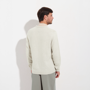Man wearing a light-colored sweater against a white background