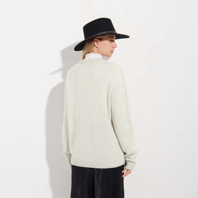 Person wearing a cream sweater and black hat on a white background