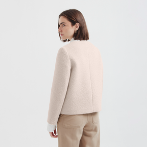 Woman wearing a cream jacket and beige pants on a white background