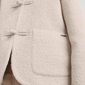 Close-up of a cream textured coat with buttons on a light background