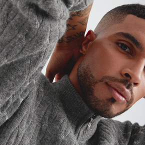 Man wearing a gray sweater with a neutral background