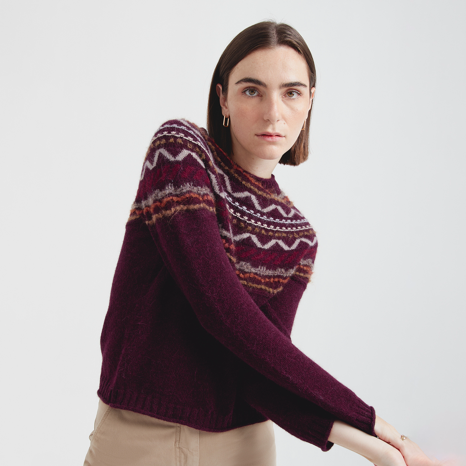 Woman wearing a patterned sweater on a plain background