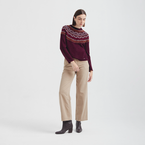 Person wearing a patterned sweater and beige pants on a white background