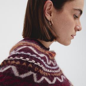 Close-up of a person wearing a patterned sweater with a white background
