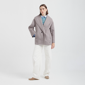 Person wearing a gray coat, blue shirt, white pants, and brown shoes on a white background
