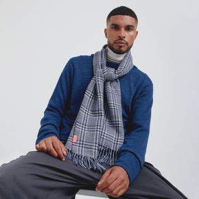 Man wearing a blue sweater and blue plaid scarf against a white background