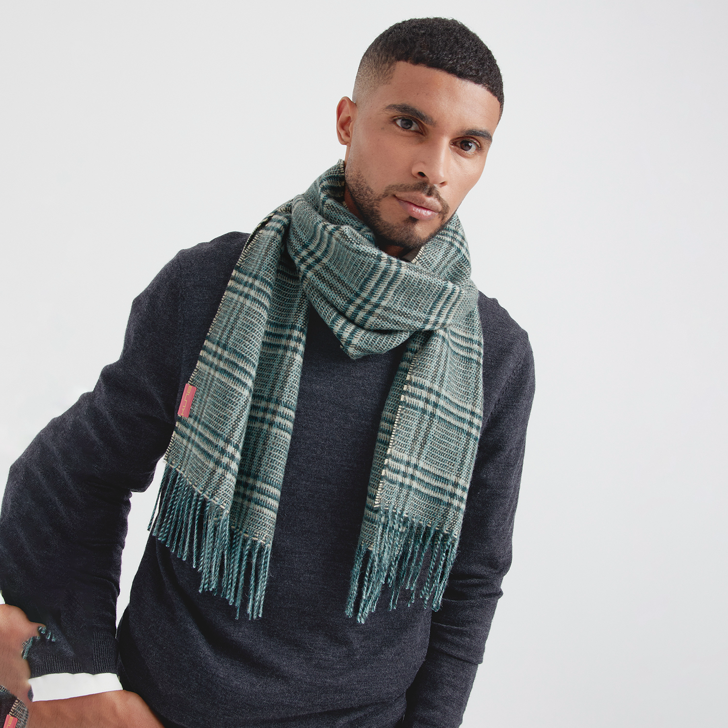 Man wearing a green plaid scarf against a plain background