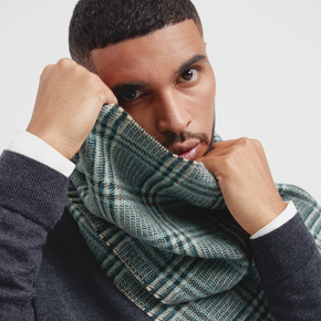 Man wearing a green plaid scarf with a neutral background