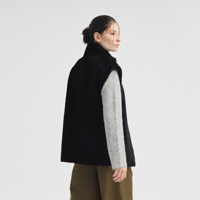 Woman wearing a black vest over a gray shirt on a white background