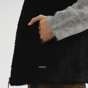 Person wearing a black fleece jacket with a brand logo on a white background