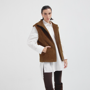 Person wearing a brown vest over a white shirt on a white background