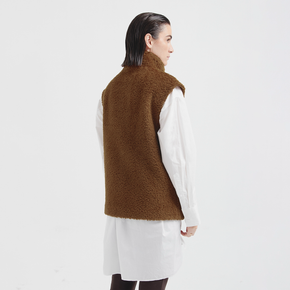 Person wearing a brown fleece vest over a white shirt on a white background