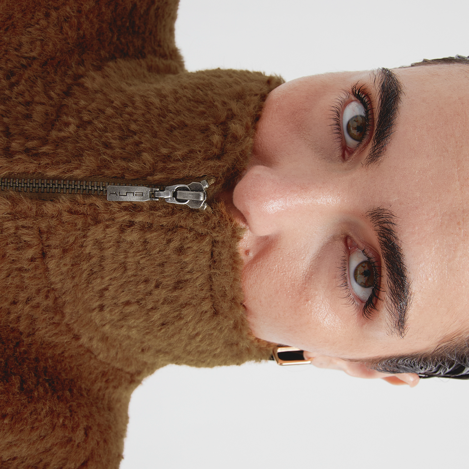 Close-up of a person wearing a brown vest with a white background