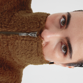 Close-up of a person wearing a brown vest with a white background