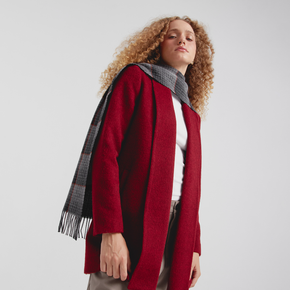 Woman wearing a red coat and plaid scarf on a white background