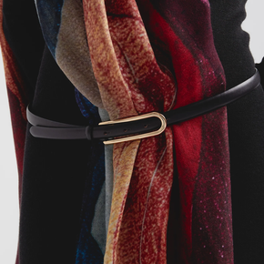 Close-up of a belt with a gold buckle on a multicolored shawl background