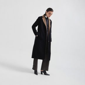 Person wearing a long black coat on a white background