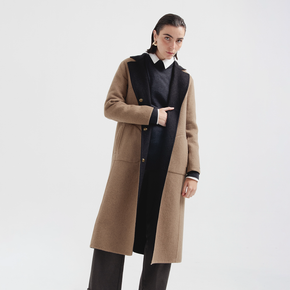 Person wearing a brown coat over a black outfit on a white background