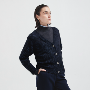 Person wearing a dark blue knitted cardigan on a light gray background