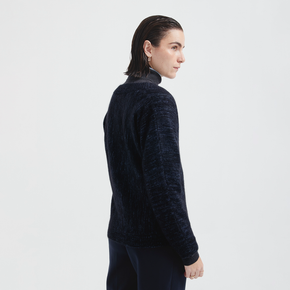 Person wearing a dark blue textured sweater on a light gray background