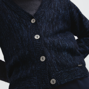 Close-up of a dark blue textured cardigan with buttons on a white background