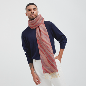 Man wearing a navy sweater and pink striped scarf on a white background