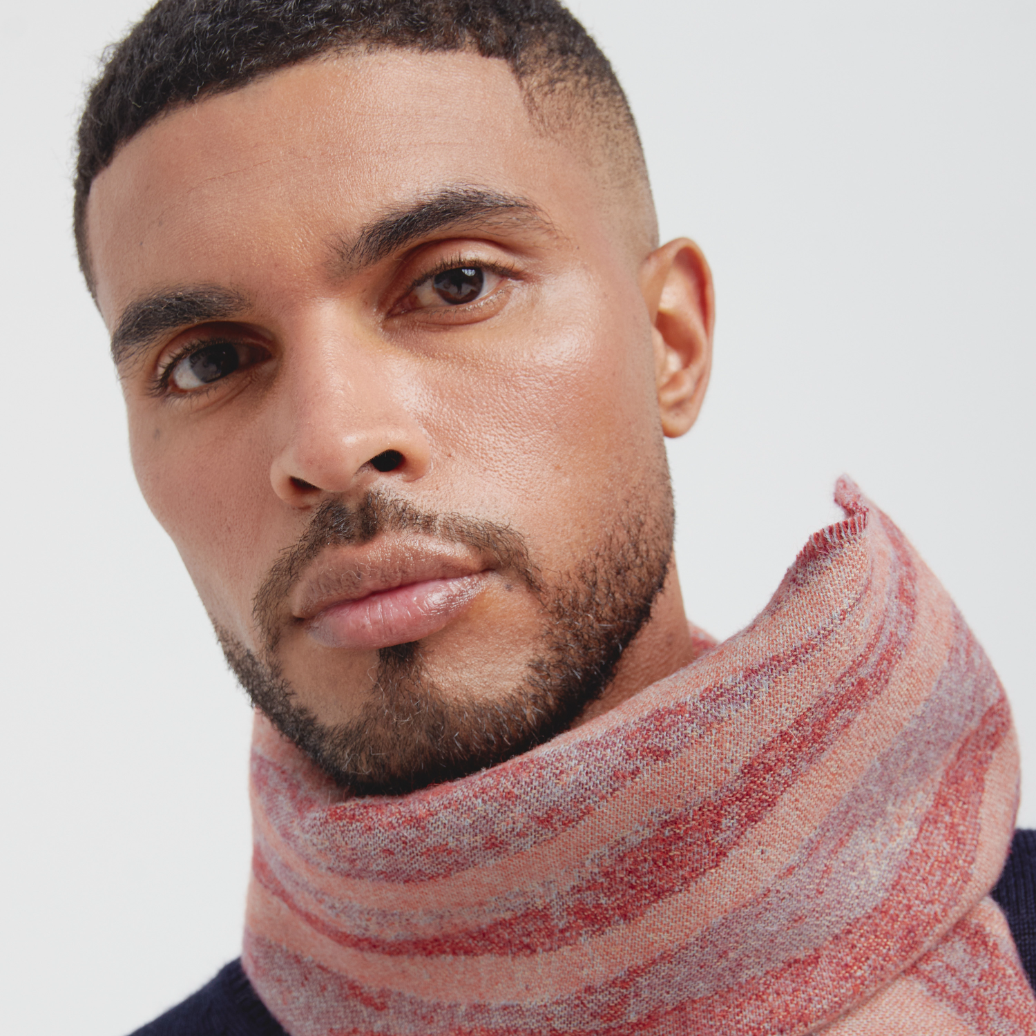 Man wearing a striped scarf against a plain background