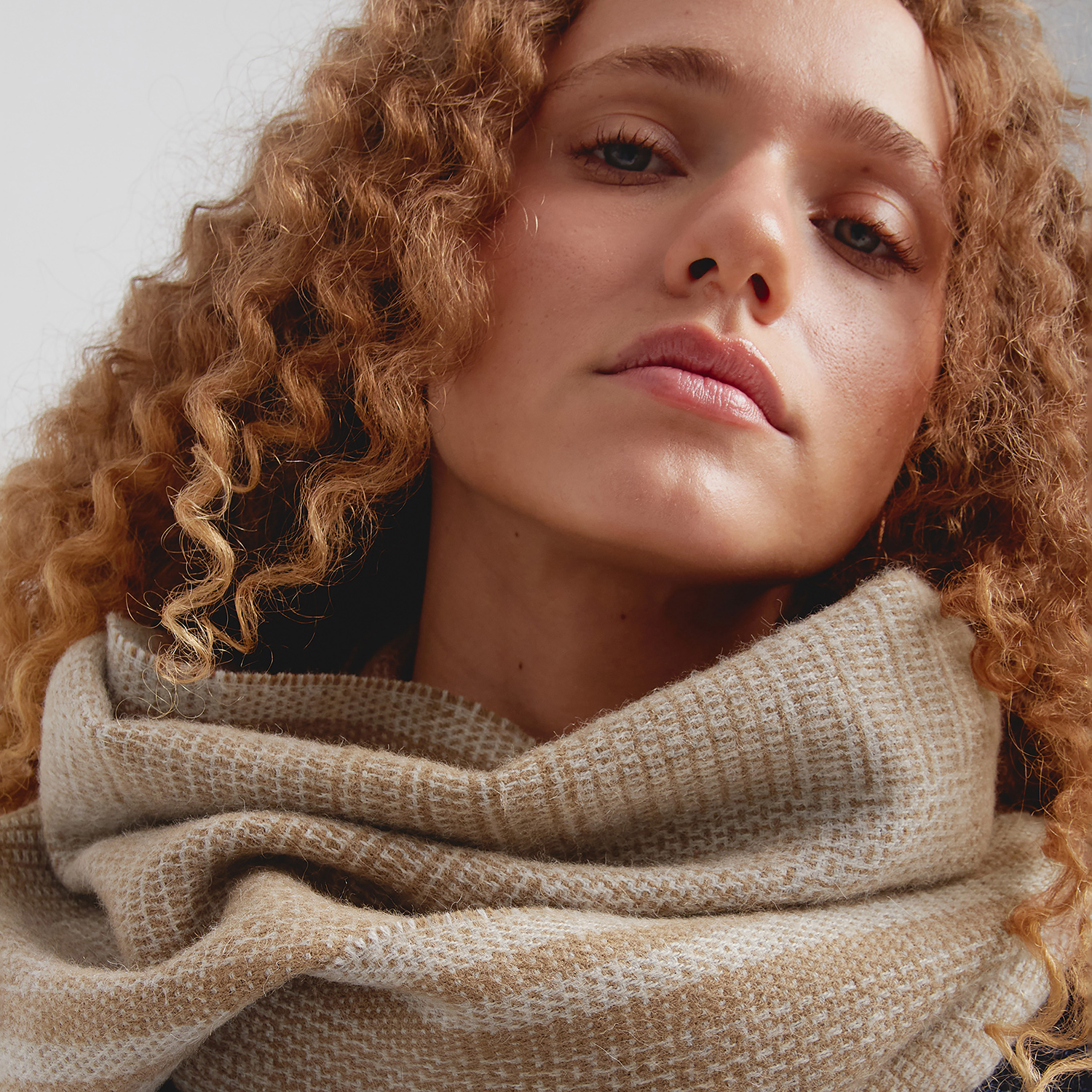 Close-up of a woman wearing a beige scarf with a neutral background