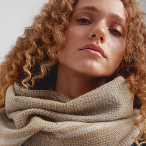 Close-up of a woman wearing a beige scarf with a neutral background