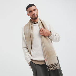 Man wearing a beige scarf and sweater on a white background